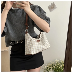 Close-up of a woven tweed shoulder bag in beige and grey with a slim leather strap