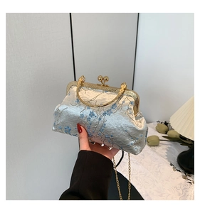 Detail of vintage blue brocade evening bag with floral embroidery and golden metal handle