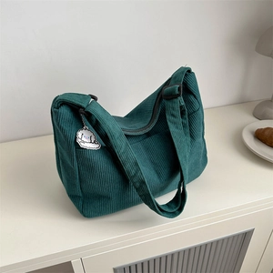 Dark green corduroy Hobo bag with puppy pendant shown in a cozy home setting