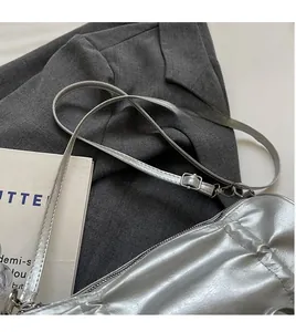 Detail of adjustable PU leather shoulder strap with silver buckle on metallic silver bag