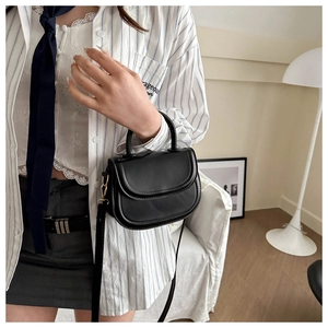 Detailed close-up of a black PU saddle bag featuring elegant gold metal hardware accents