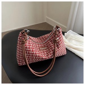 Detail of tweed shoulder bag with leather handles and Fashion label on dark surface