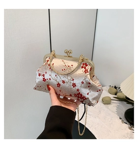 Detail of elegant cream satin handbag featuring red plum blossom embroidery and metal clasp