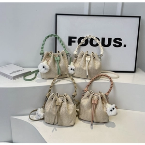 Detail of woven bucket bags in mint green and cream white with cute monster charms