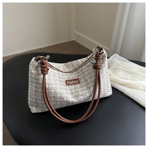 Detail of tweed crossbody bag featuring beige weave, brown straps, and Fashion leather patch