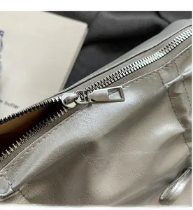 Detail of a smooth metallic silver zipper and textured fabric on a trendy underarm bag