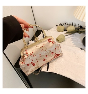 Detail of vintage hand-held bag with red plum blossoms and carved metal handle