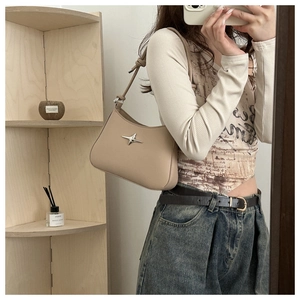 Detail of beige crescent underarm bag with silver star hardware and adjustable strap
