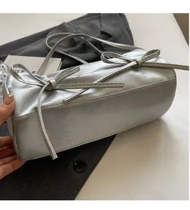 Detail of silver pillow bag featuring soft pleated PU fabric and metallic bows