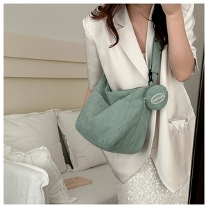 Detailed texture of green corduroy tote bag with round coin purse on wide shoulder strap