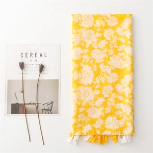 Close-up of yellow cotton-linen scarf featuring white daisy prints and fringe tassel detail