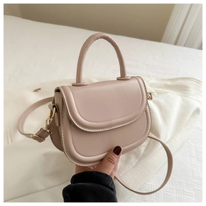 Detailed view of beige PU leather handbag with smooth flap and pale gold hardware accents