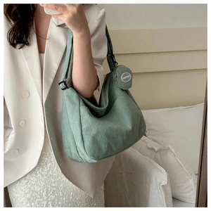 Detail of mint green corduroy dumpling bag with adjustable strap and mini round pendant