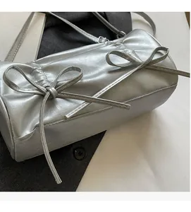 Detailed view of silver pillow bag featuring dual leather bow accents and metallic texture