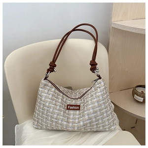 Nahaufnahme der beigen Tweed-Textur und des braunen Lederriemens mit Knotendetail an der Tasche