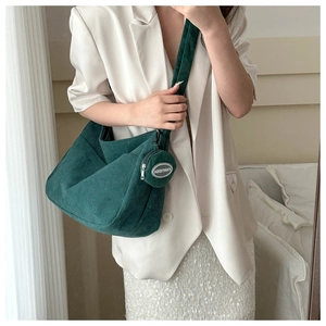 Detail of dark green corduroy crossbody bag with wide strap and matching round charm