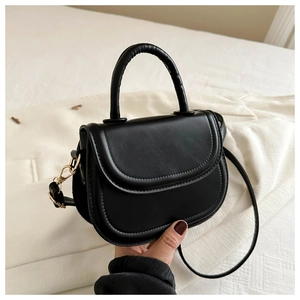 Detail of minimalist black saddle bag with smooth PU leather and gold metal buckle