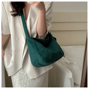 Detailed view of large dark green corduroy crescent crossbody bag worn by a model