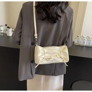 Close-up of creamy white satin cylinder bag with elegant pleats and delicate bow details