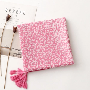 Detail of pink leaf print scarf featuring long fringes and soft cotton-linen texture