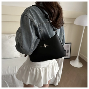 Detail of black leather shoulder bag featuring a silver star ornament and adjustable knot strap
