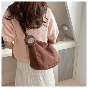 Close-up of brown corduroy crossbody bag texture and small matching round coin purse detail