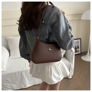 Detail of dark brown faux leather underarm bag with silver star-shaped metal ornament