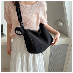 Detail of black corduroy tote with wide strap and matching round coin purse shown on model