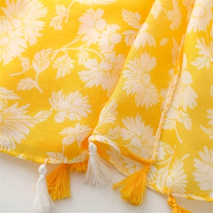 Close-up of yellow cotton-linen scarf featuring white daisy prints and fringe tassel detail