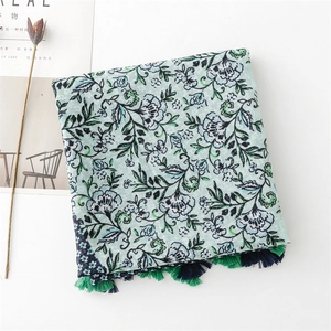 Detail of floral linen scarf with green contrast print and delicate tassels decoration