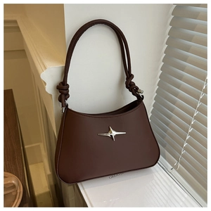 Detail of dark brown leather handbag with silver star emblem and knotted shoulder strap