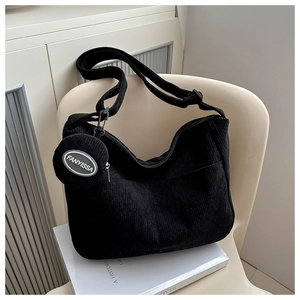 Detail of black corduroy tote bag featuring a round coin purse and ribbed texture