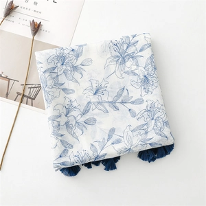 Détail d'imprimé floral bleu sur écharpe en coton lin avec glands bleu marine sur fond blanc