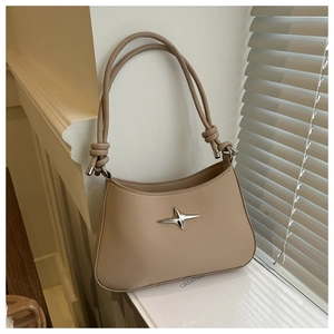 Detail of beige leather bag featuring silver star emblem and knotted shoulder strap