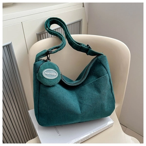 Detail of green corduroy tote bag with adjustable strap and small round pouch attachment
