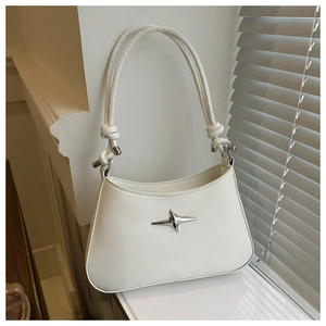 Detailed view of white leather underarm bag featuring silver star hardware and knot strap