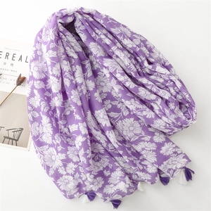 Detail of lavender scarf with white daisy print and fringe edges on a styled background