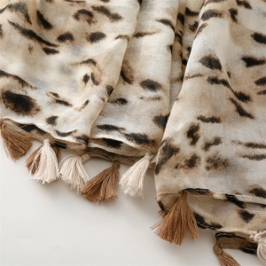 Detailed close-up of leopard print scarf fabric texture with decorative fringe tassels