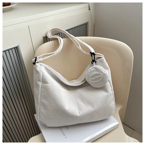 Detail of white corduroy tote bag with side coin purse pendant and thick shoulder strap