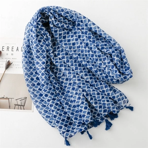 Linen feel scarf with blue fish scale print and tassel details in minimalist setting