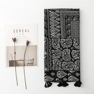 Detailed view of the blue floral paisley pattern and black tassels on the linen scarf
