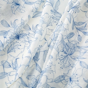 Gros plan sur une écharpe légère en coton et lin blanche avec motif floral de lys bleu
