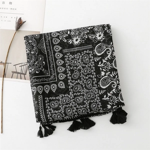Close-up of paisley print shawl with black tassels and minimalist decor background
