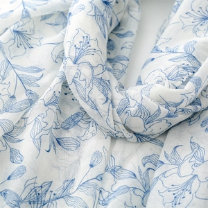 Gros plan d'une écharpe en coton et lin blanche avec motif de lys bleus et texture légère