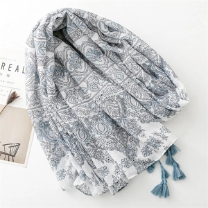 Blue ethnic floral print scarf with tassels on a white background with decorative items
