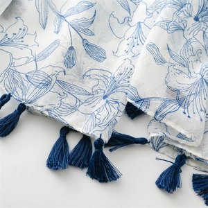 Détail de motif de feuilles bleues sur écharpe en coton et lin avec glands bleus