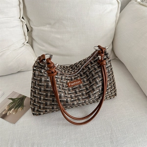 Schultertasche mit Karomuster, braunen Ledergriffen und Silberdetails in sanftem Licht