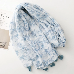 Lightweight cotton-linen scarf with blue floral prints and tassel edges on white base