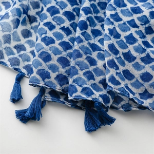 Detailed close-up of blue scale-patterned scarf fabric with elegant tassel fringe edge