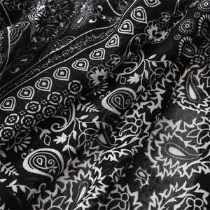 Close-up of black and white paisley floral patterns on a soft cotton-feel scarf fabric
